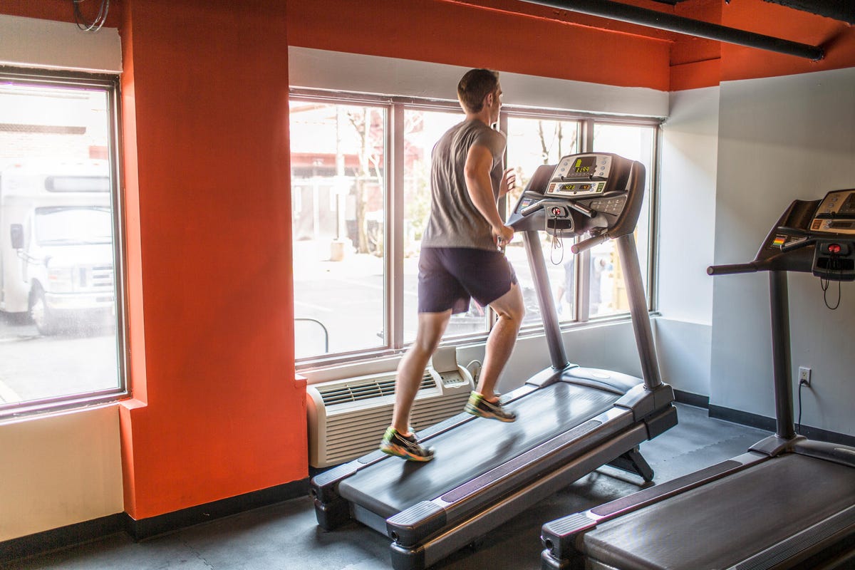 Exhausted mid adult man running uphill on gym treadmill