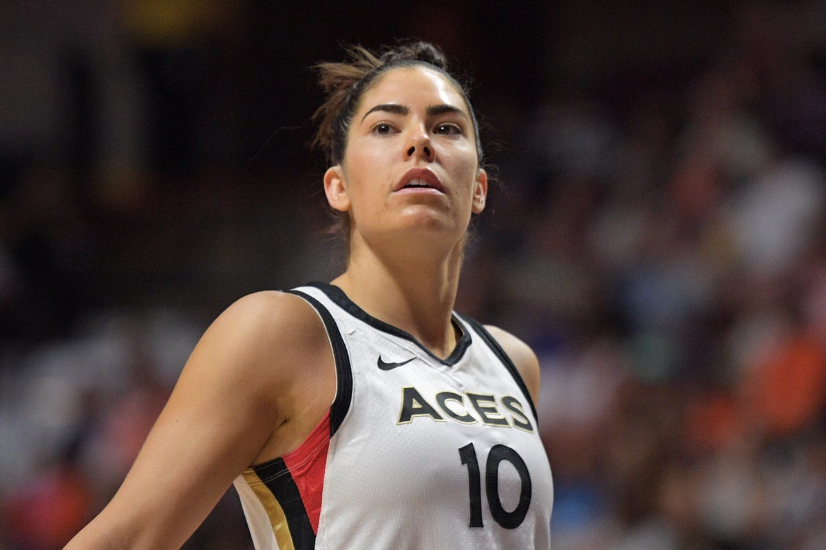Kelsey Plum, in a white Aces uniform, looks up