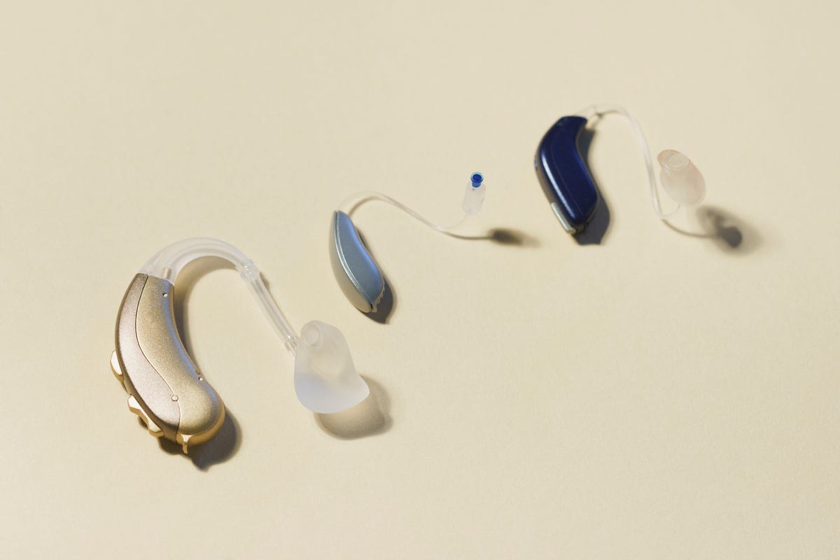Three behind-the-ear hearing aids on a yellow background