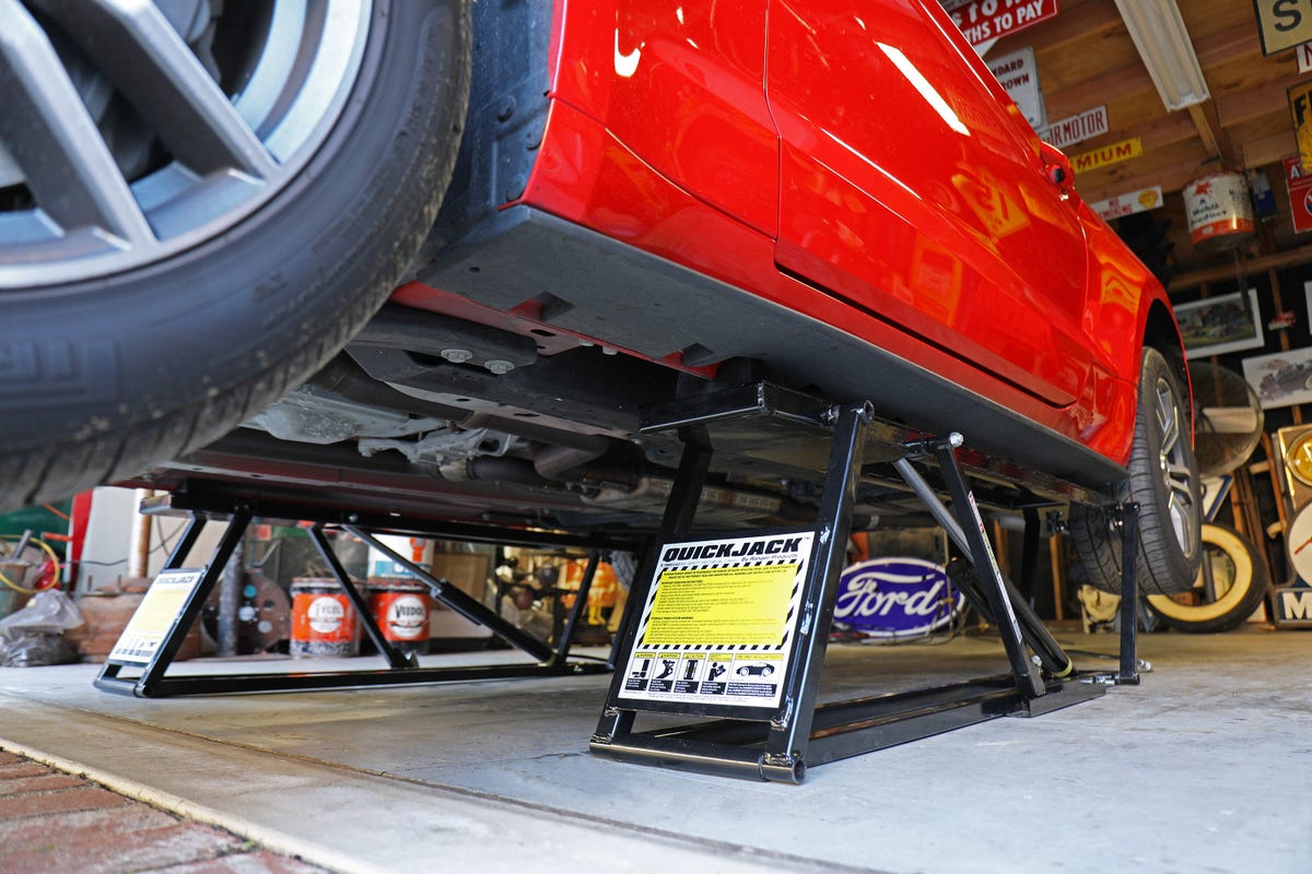A close-up of the underneath of a car being held up by portable auto lifts. 
