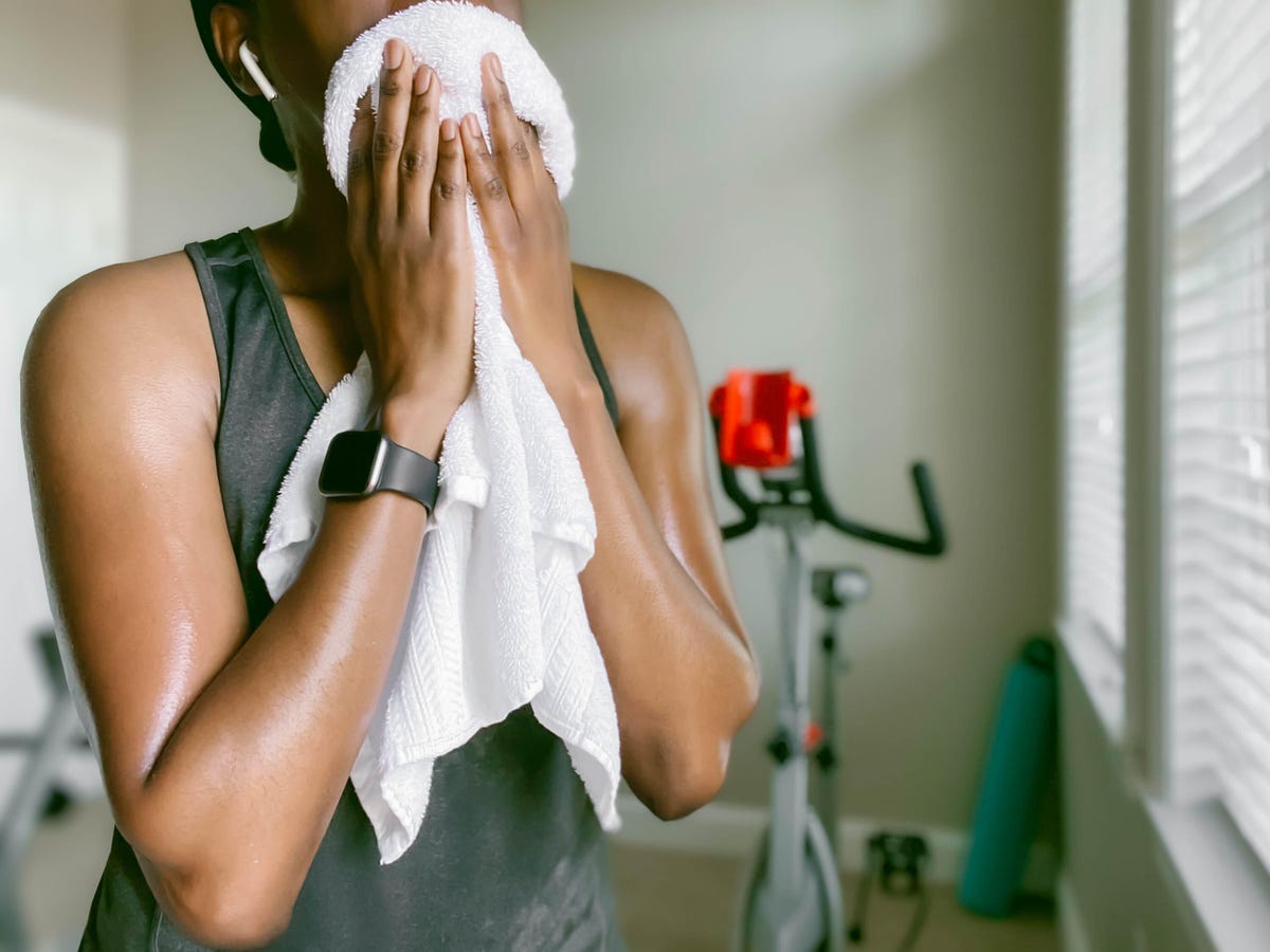 a woman wipes sweat from her face with a towel