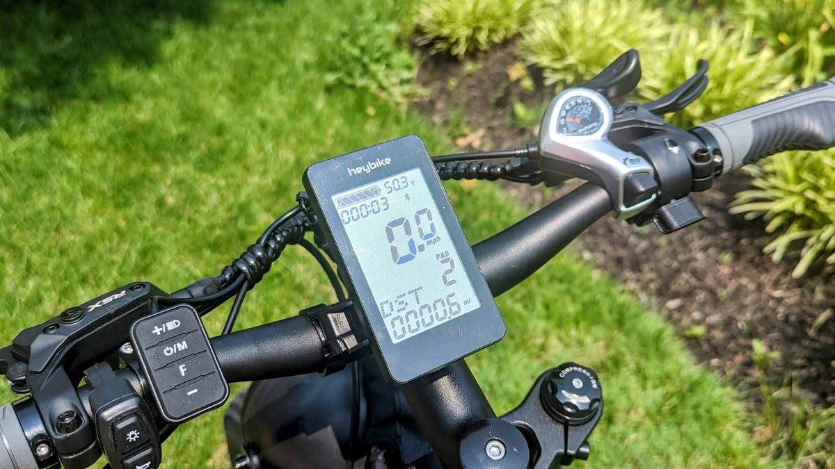 The handlebars of an e-bike with an LED display in the center