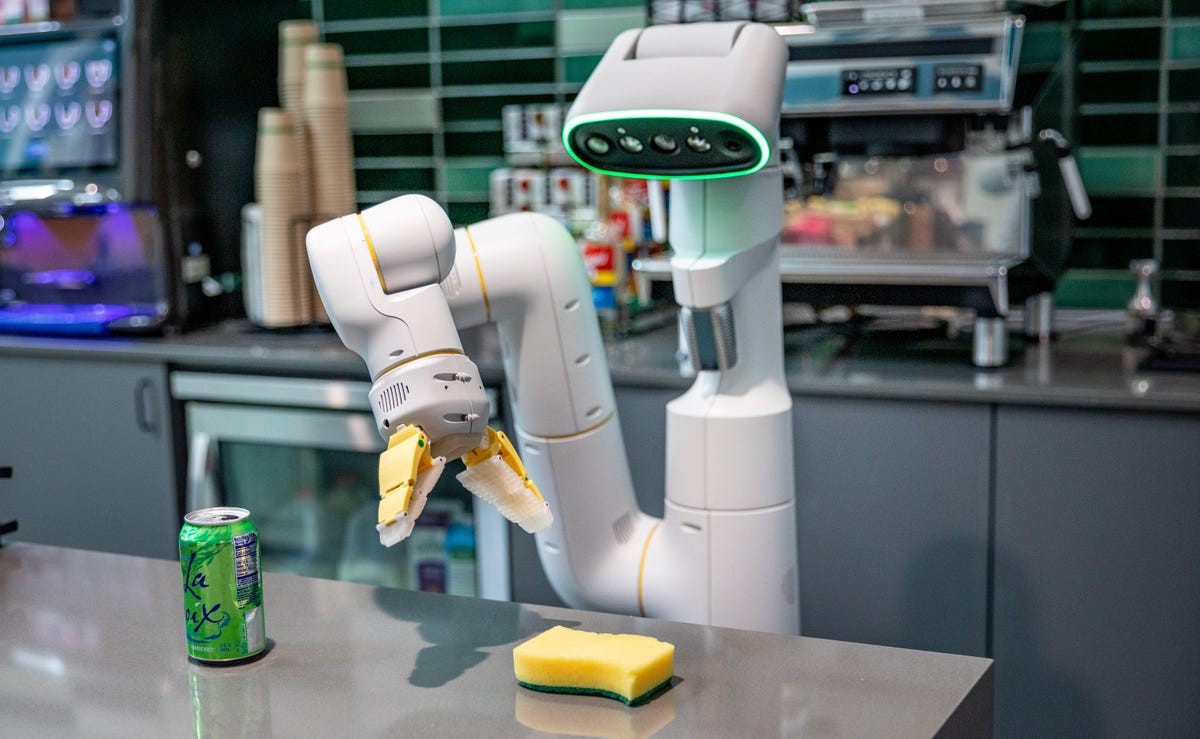 A Google robot's mechanical arm reaches for bright yellow sponge.