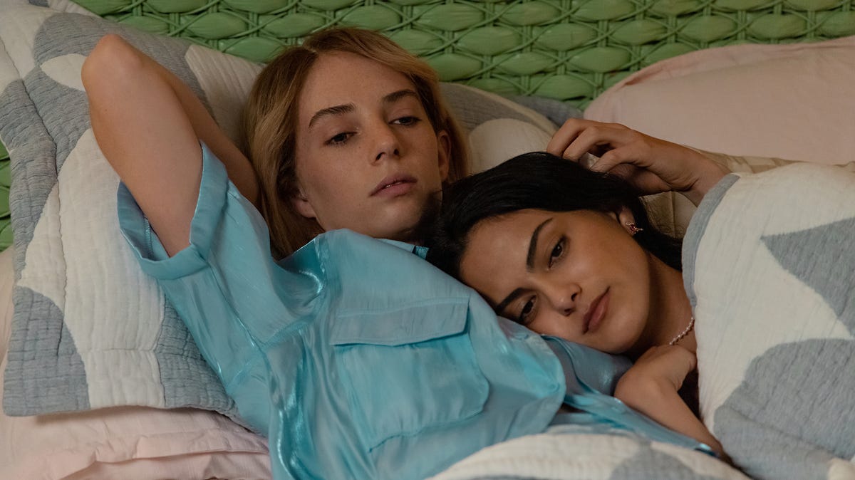 Maya Hawke as Eleanor and Camila Mendes as Drea, lying in bed