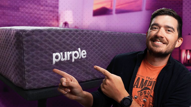 The Purple Restore mattress against a colorful background and a man in a sweatshirt in the front.
