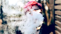 A young person blowing vapor or smoke that covers their face
