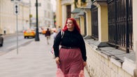 Red-haired plus size woman walks down street.