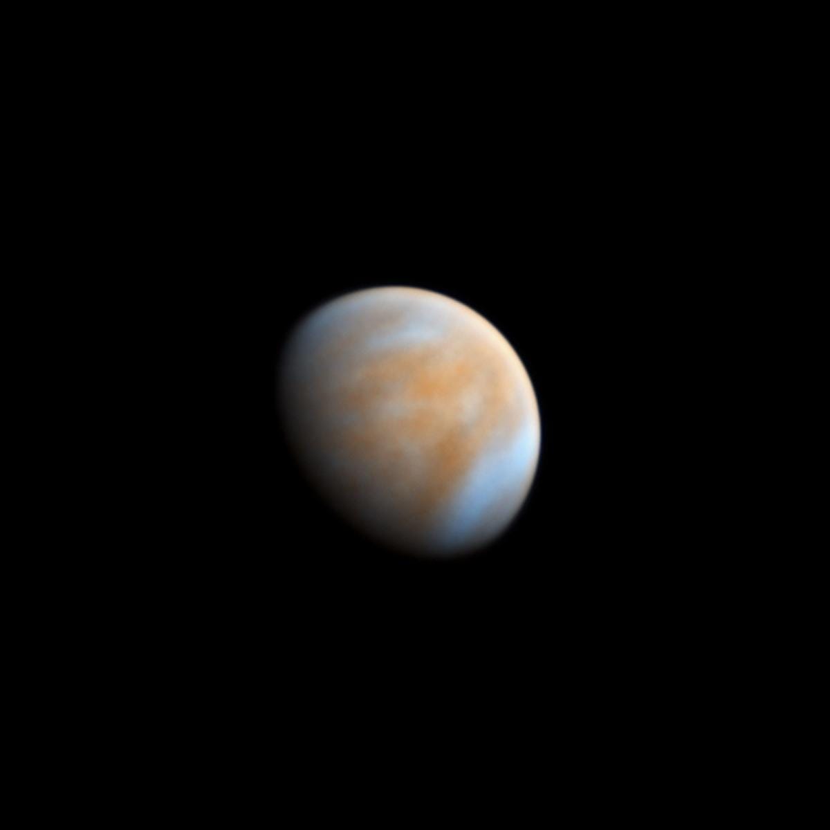Venus against black space. The planet is partially hidden, the rest look like a soft orange and white marble.