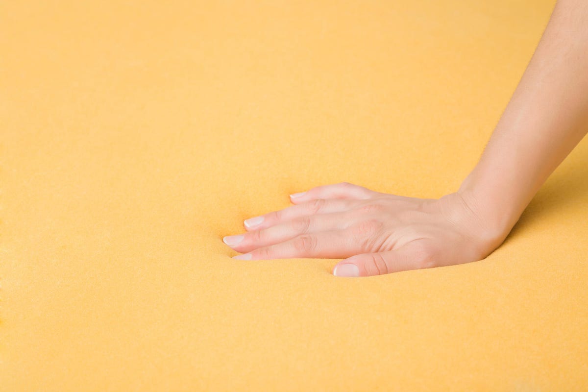 Hand pressing yellow foam mattress surface