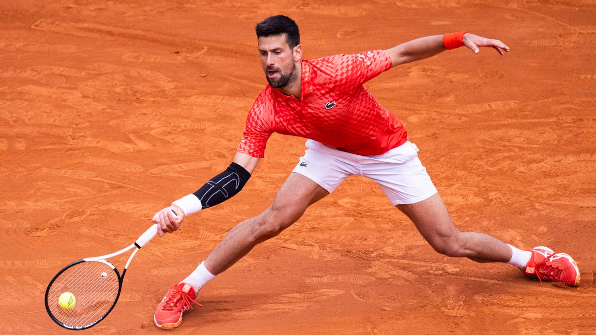 Le joueur de tennis Novak Djokovic s'étire pour le ballon alors qu'il joue sur un court en terre battue.
