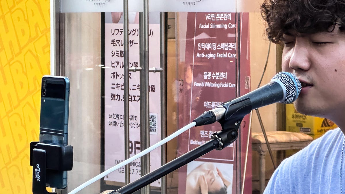 A street performer with a Galaxy Z Flip mounted on his microphone stand in Seoul. 