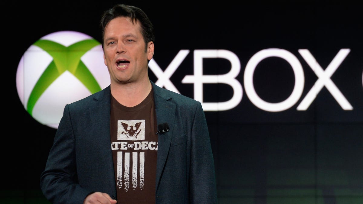 phil spencer standing on stage in front a screen showing xbox logo
