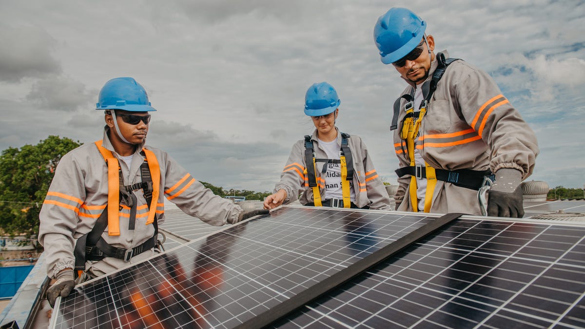 Three people installing a solar panel