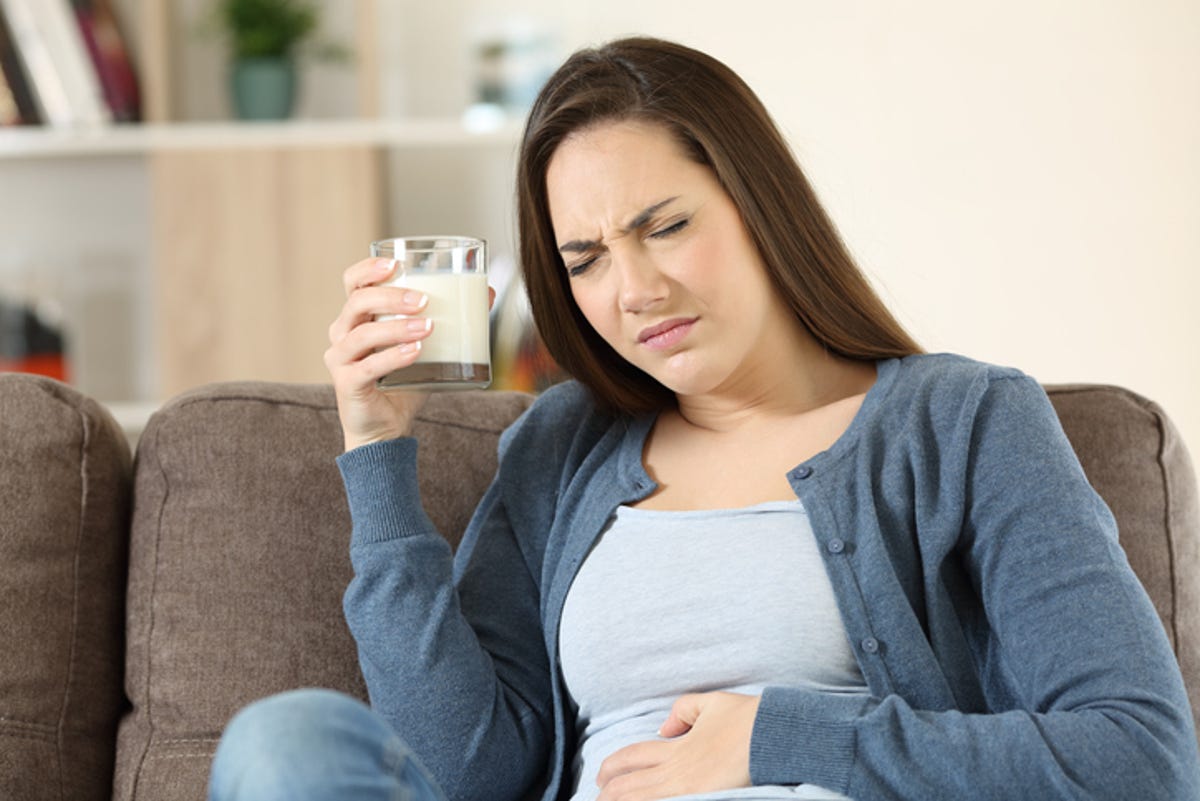 Woman holding her stomach in discomfort after drinking milk