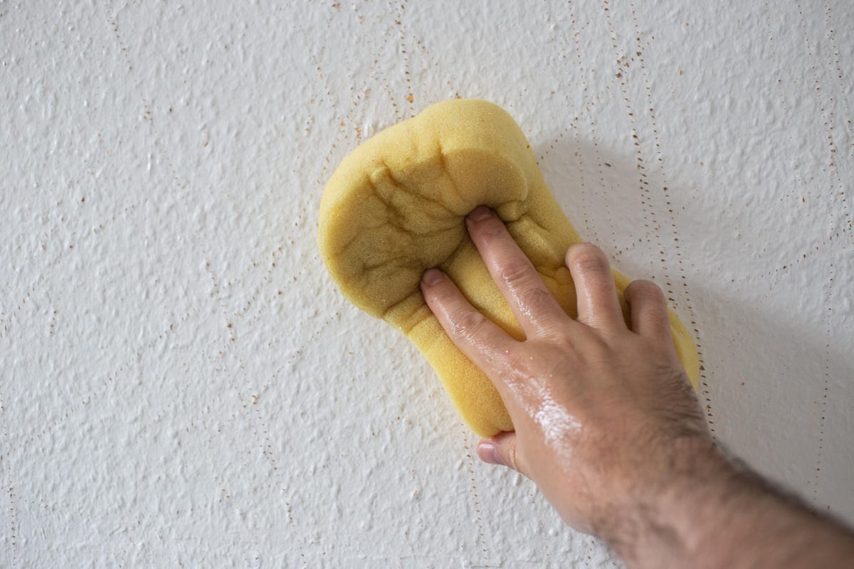 Image showing hand holding wet sponge against a wall
