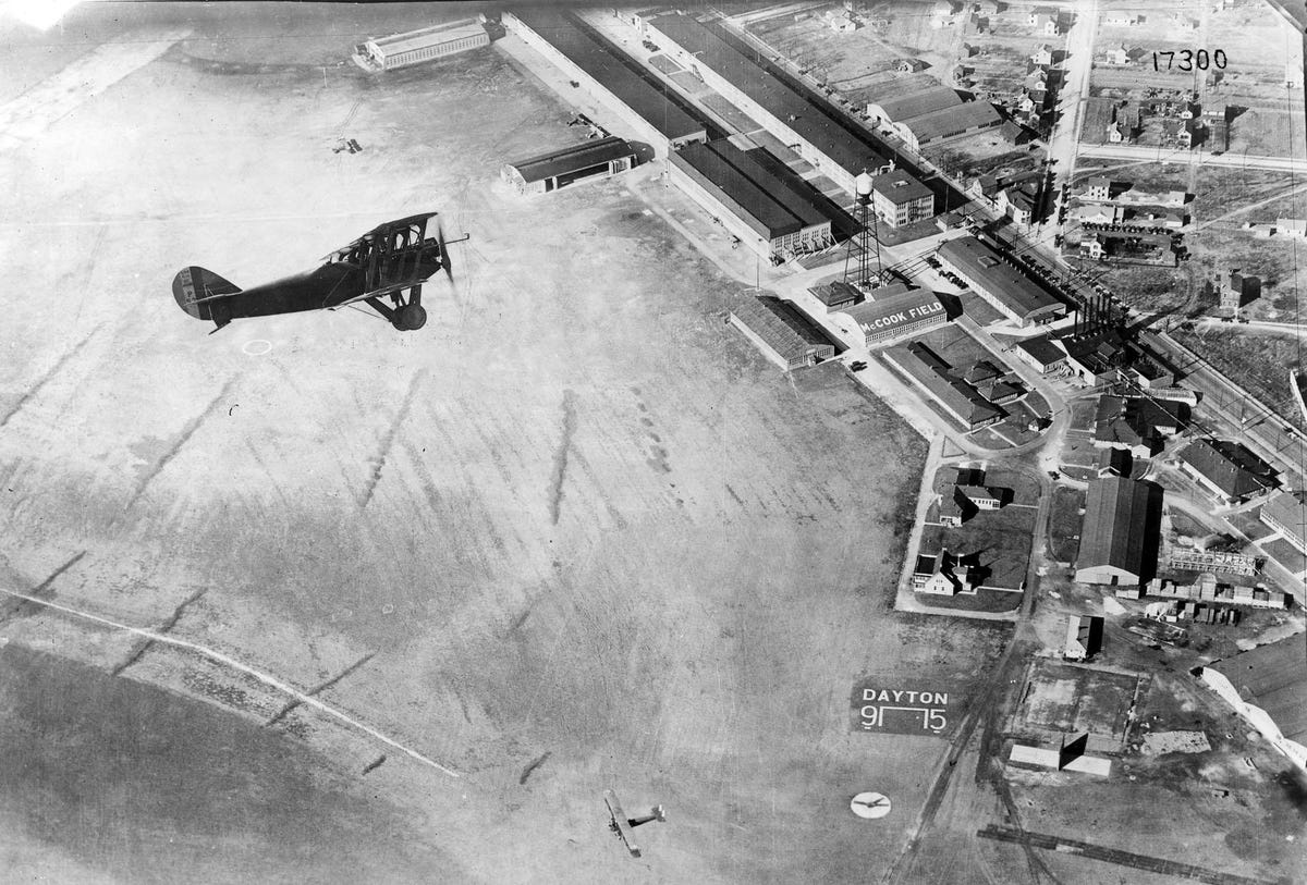 Aerial photo looking down at a Packard-Le Père LUSAC-11 biplane flying over an airfield