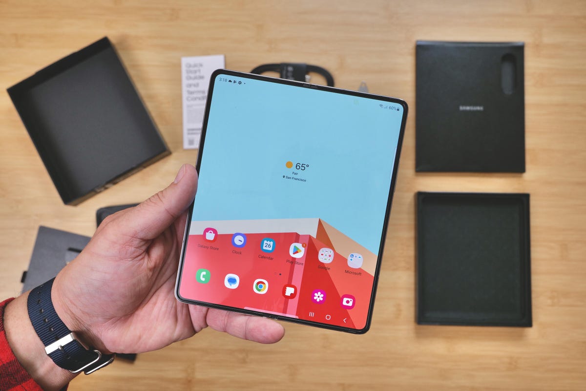 A hand holding a Samsung Galaxy Z Fold 5 above the contents of its box