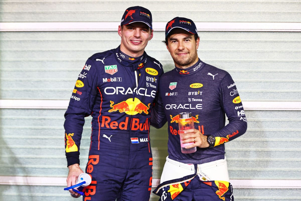 Max Verstappen and Sergio Perez pose together in their blue Red Bull uniforms.