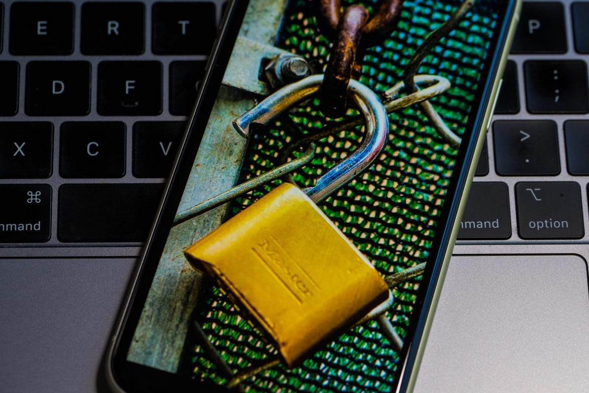 Unlocked padlock and fencing on a phone screen, with a computer keyboard in the background