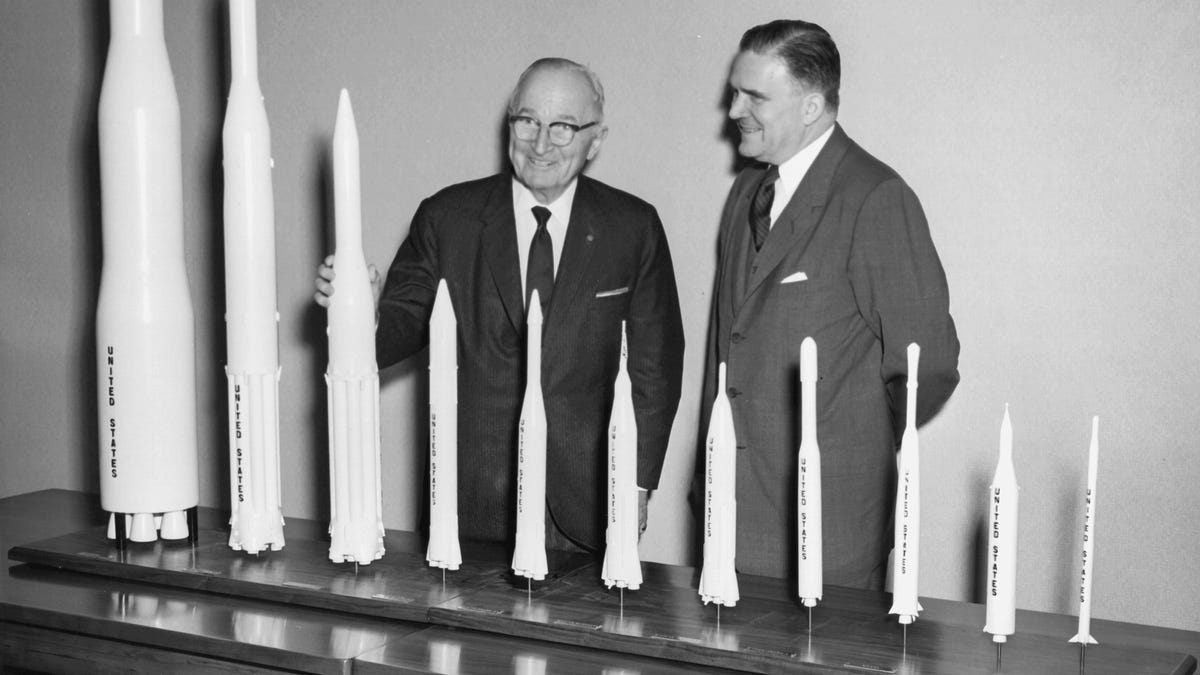 James Webb and Harry Truman stand in front of many rocket models, in this black and white image.