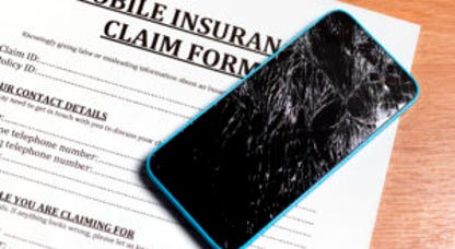 Broken cell phone resting on mobile insurance claim paperwork