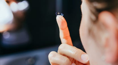 Woman with contacts on her fingertip.