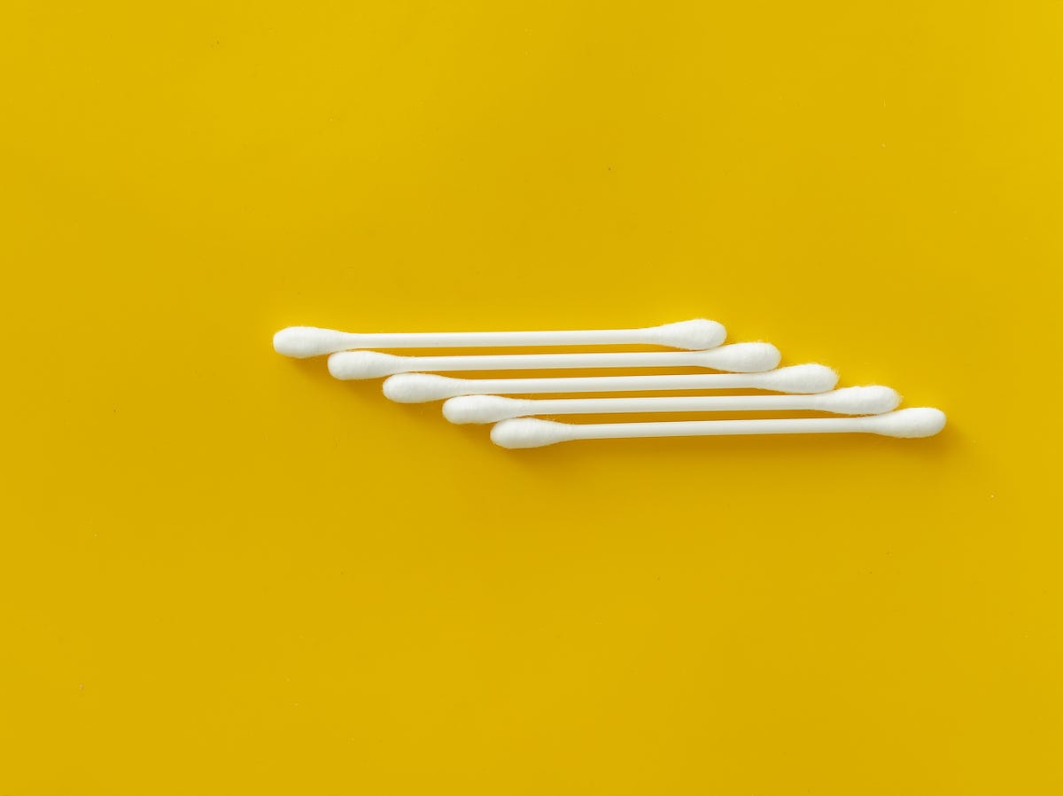 Row of five Q tips on yellow background