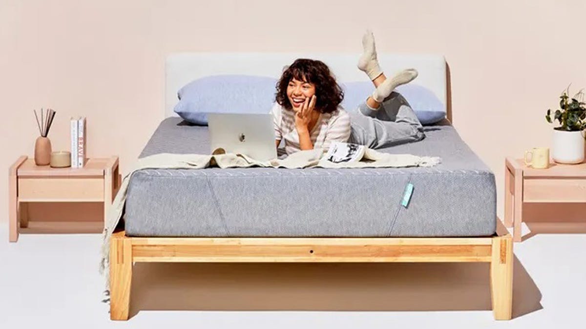 A woman lies on her stomach with her laptop on top of the Siena memory foam mattress.