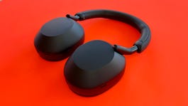 Black Sony WH-1000XM5 headphones are displayed against a red background.