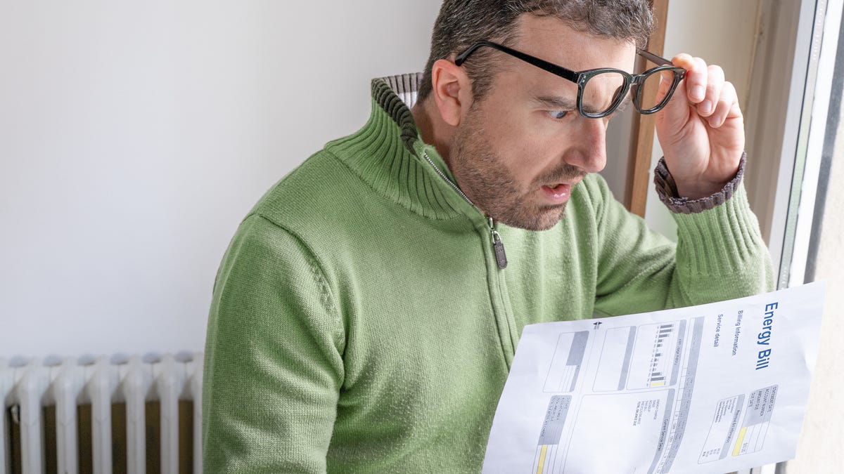 A man with a shocked look on his face looking at an energy bill.