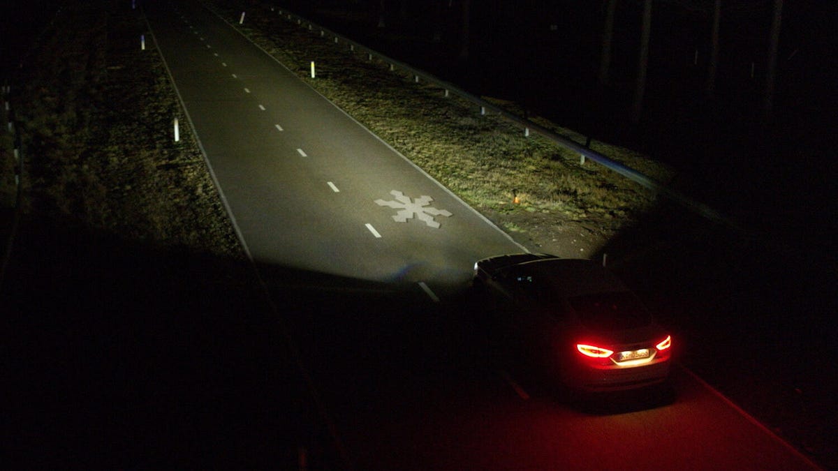 a car driving at night projects a snowflake onto the road from its headlights