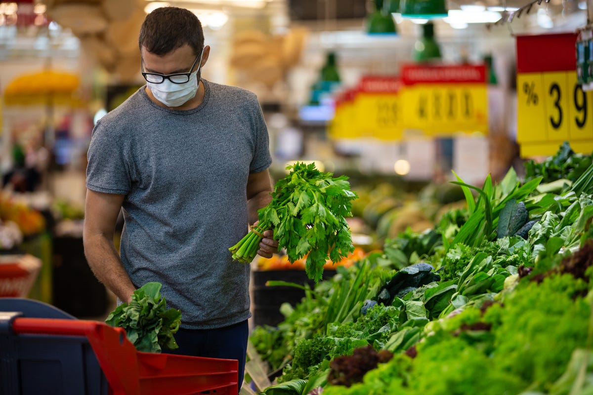 Masked person shops for green produce at the store.