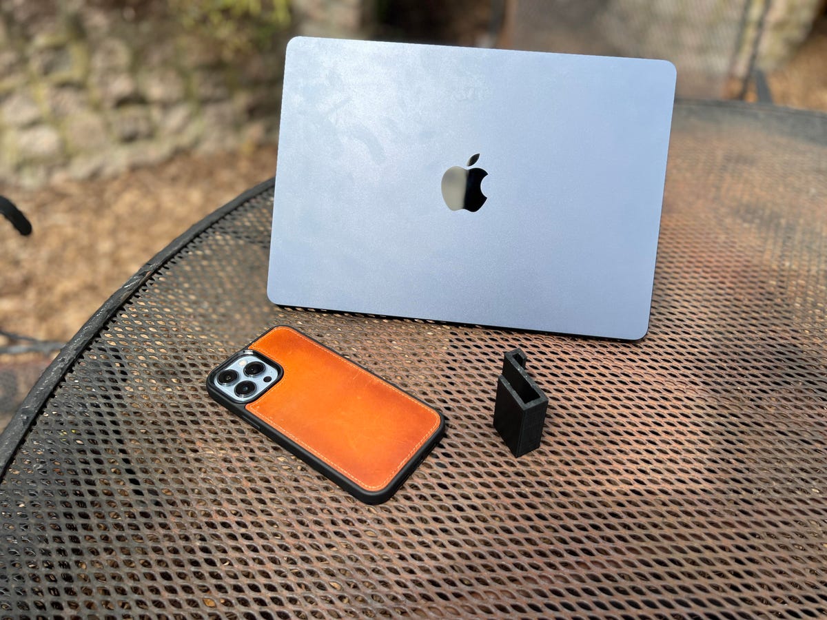 A MacBook, a phone and a clip on a patio table