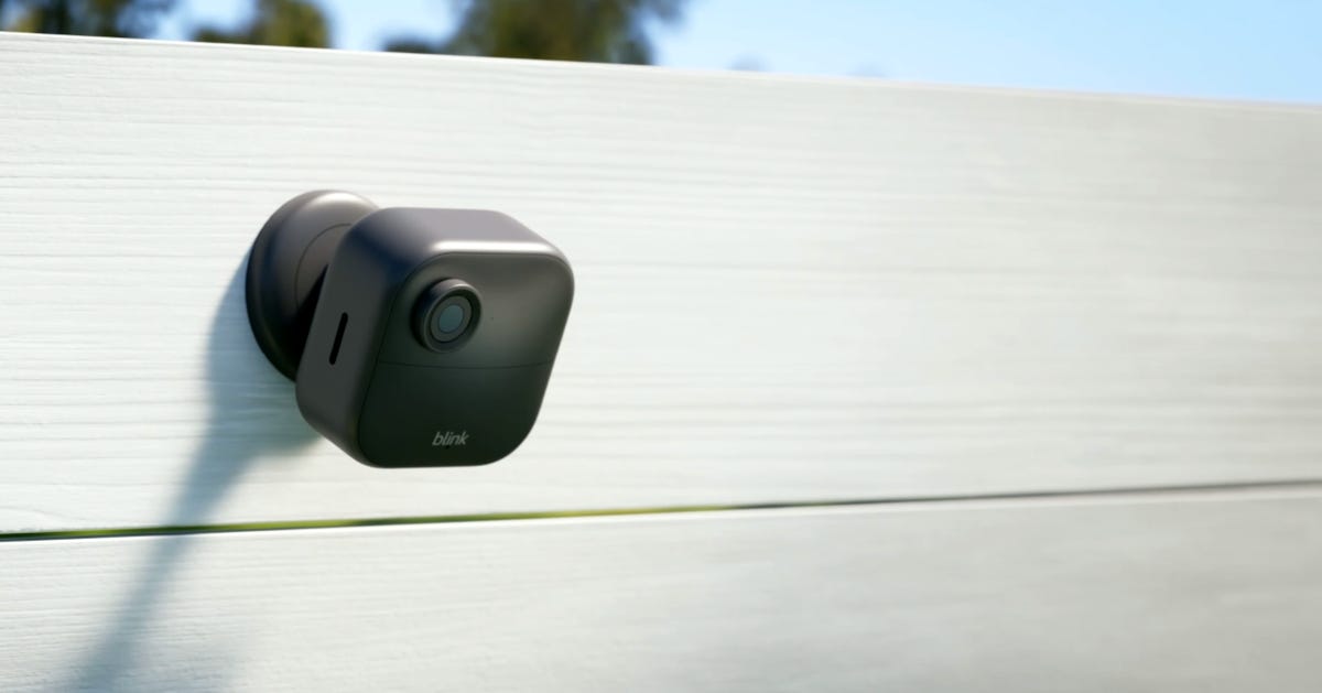 The wireless Blink Outdoor 4 security camera sits perched on a fence.