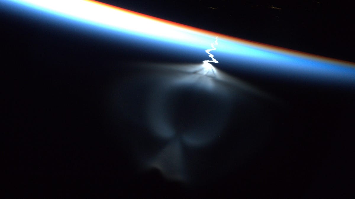 An exhaust plume shows against a dark background. Part of the plume look like a robed angel, wings extended upward.