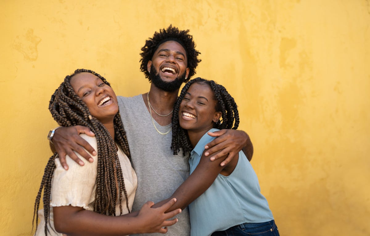 Three family members hugging in front of a yellow wall