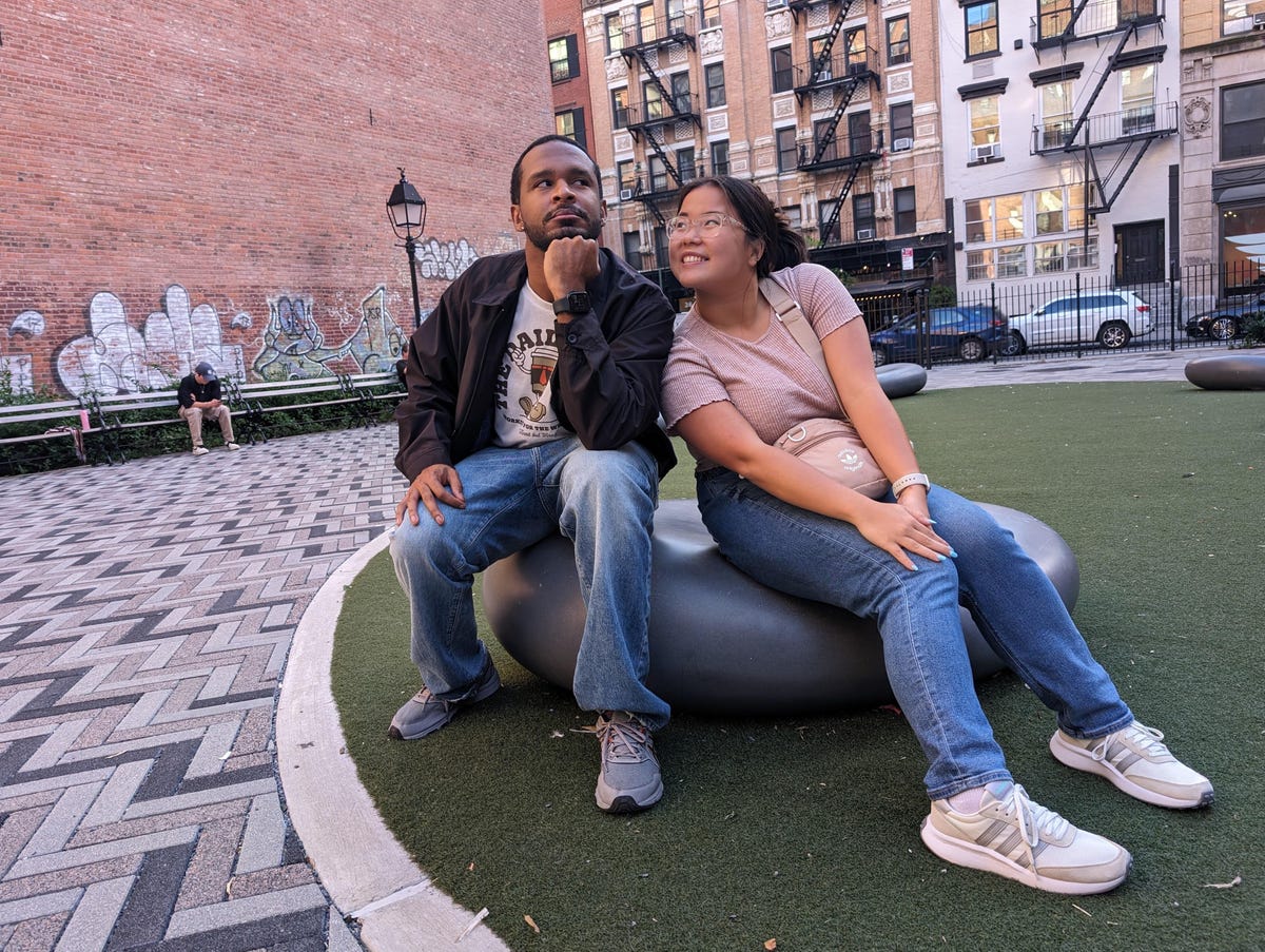 Two people sitting on a rock leaning on each other