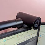 A webcam attached to a monitor with a pink background