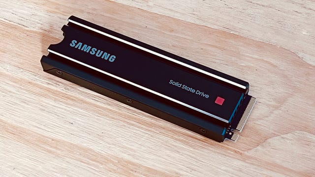 A Samsung M.2 SSD drive for expanding PS5 storage is displayed on a wooden surface.