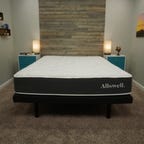 The Allswell mattress on top of a grey bed frame in between two blue and white night stands