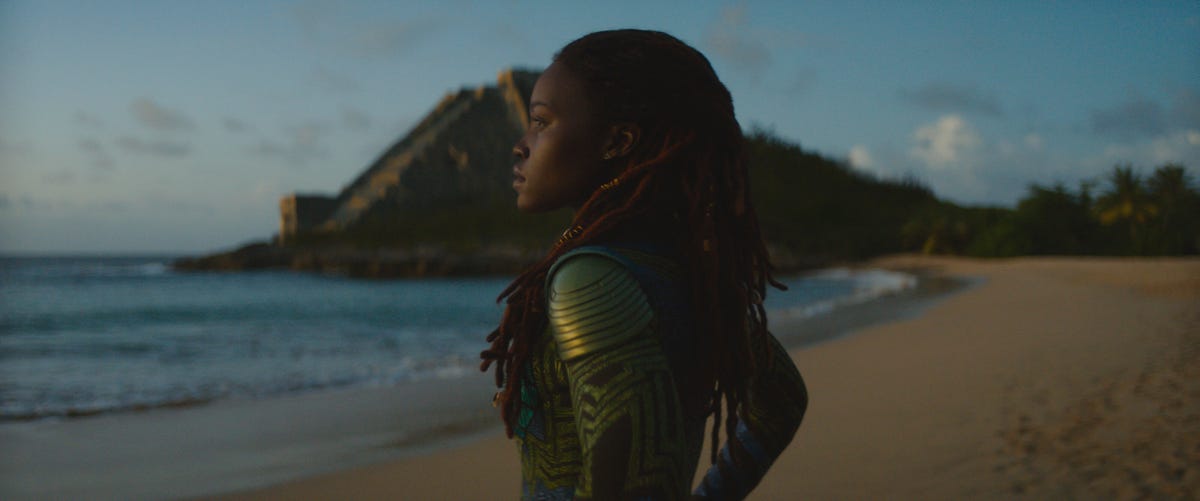 Lupita Nyong'o as Nakia stands on a beach facing water