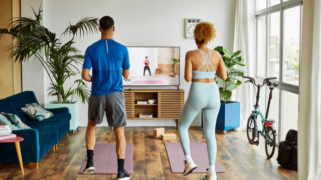a couple exercise in their living room watching a workout video