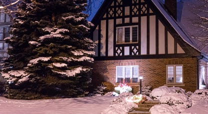 A Tudor-style house with snow on the ground out front