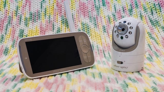 A baby monitor and screen sitting on a pastel blanket 