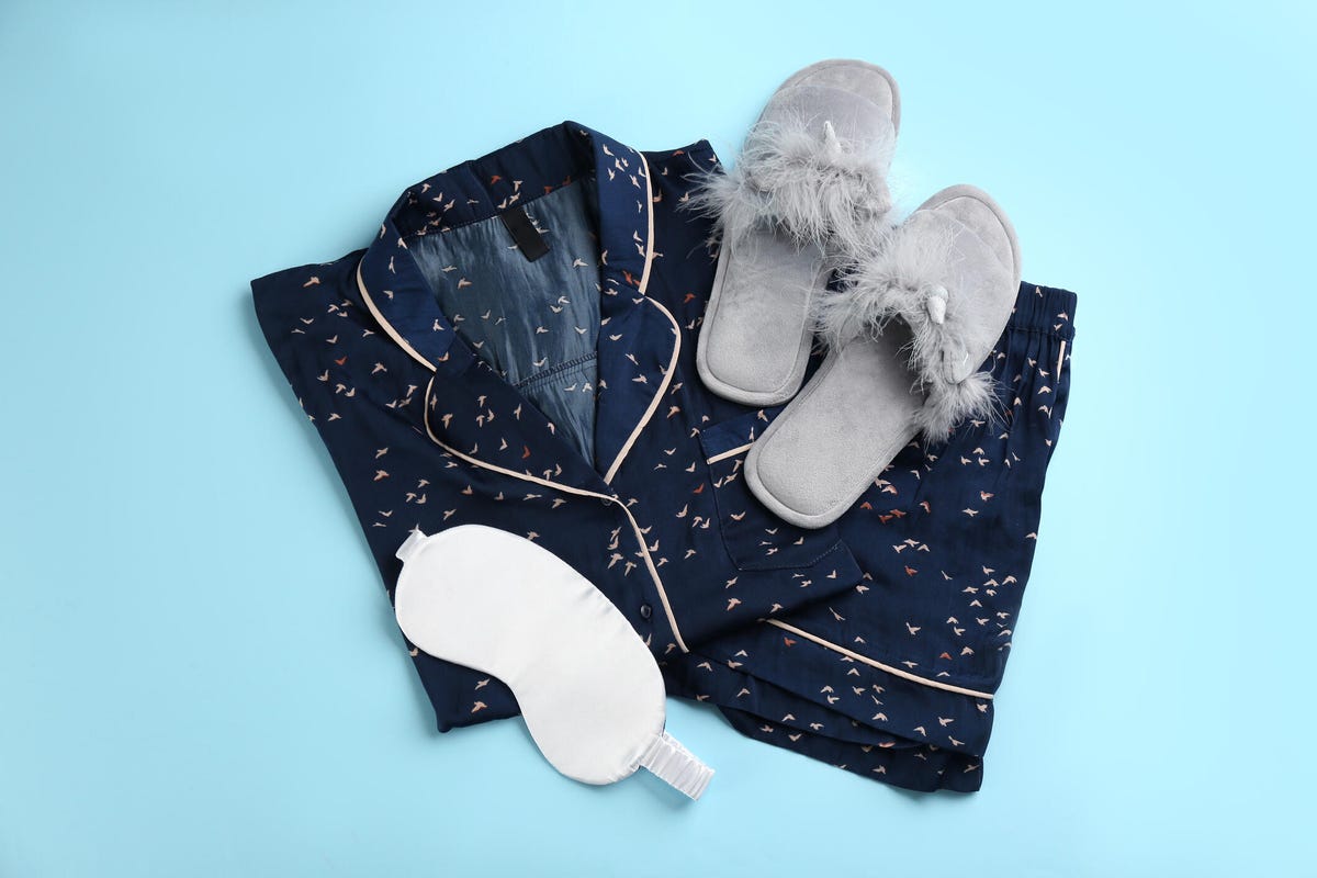 A pair of pajamas with slippers and an eye mask on top