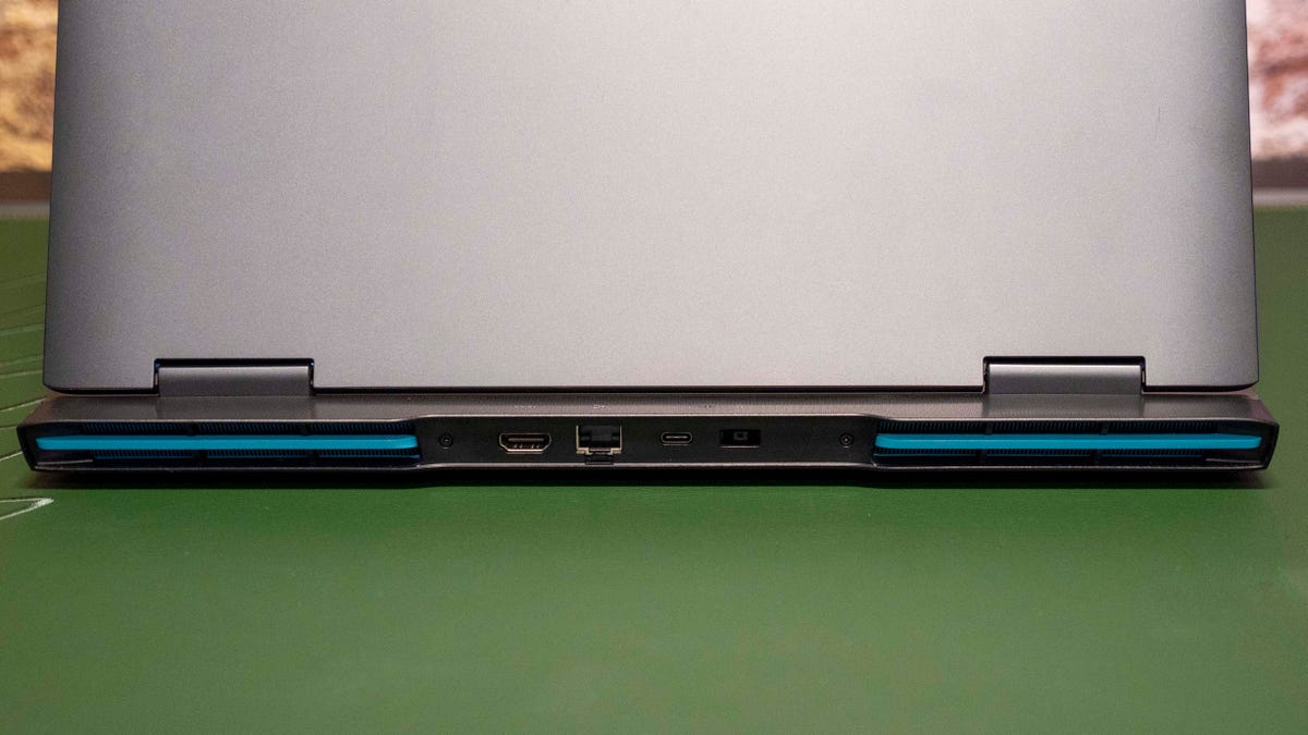Lenovo IdeaPad Gaming 3 laptop open with a rear view of its ports and sitting on a green desk mat.