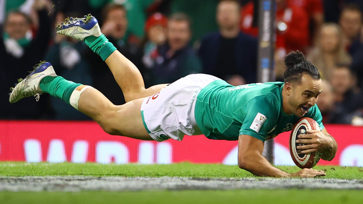 Ireland Rugby player James Lowe diving over the line to score, clutching the ball with his left arm.