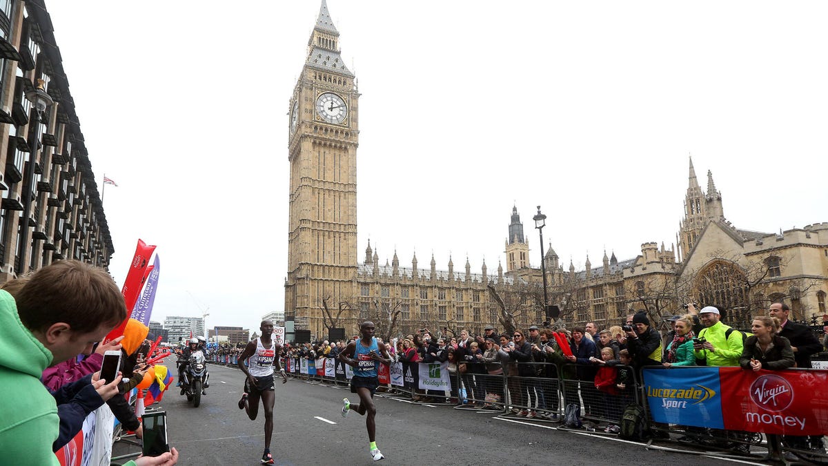 Athletes Eliud Kipchoge and Wilson Kipsang running in the London Marathon. Crows on either side of the athletes with Big Ben in the background.