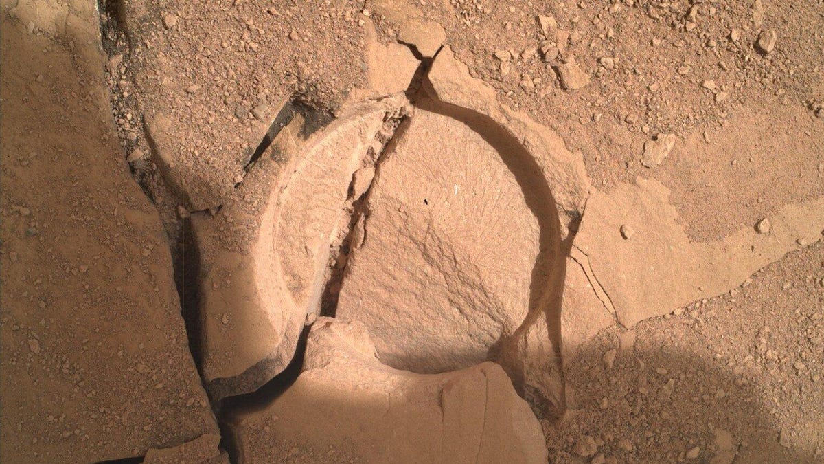 A round abrasion in a Mars rock with cracks running across it.
