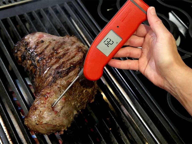 red thermometer sticking into steak on grill